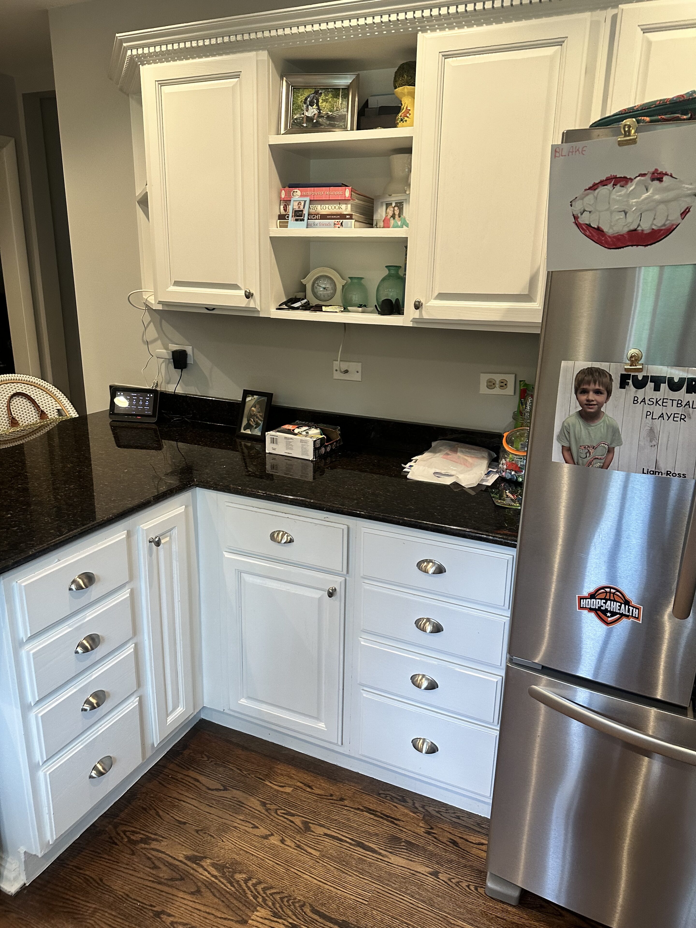 A kitchen with white cabinets and black counter tops.