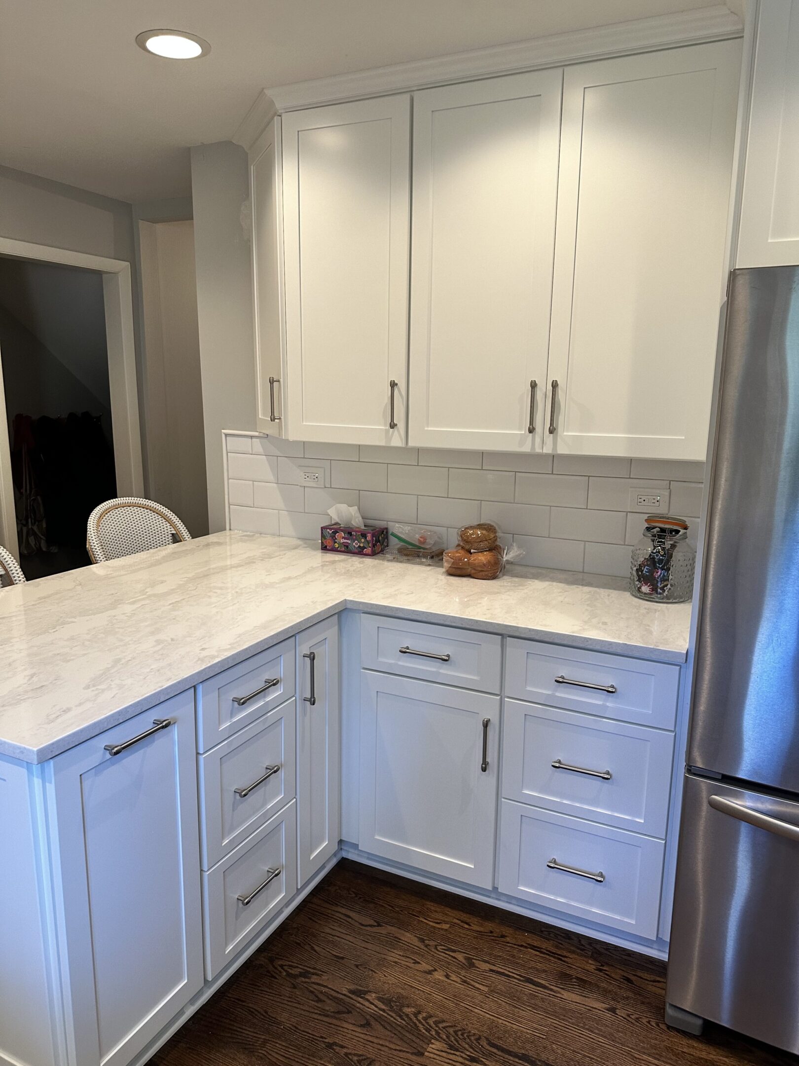 A kitchen with white cabinets and a silver refrigerator.