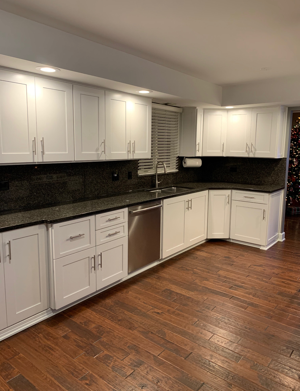 A kitchen with white cabinets and black counter tops.