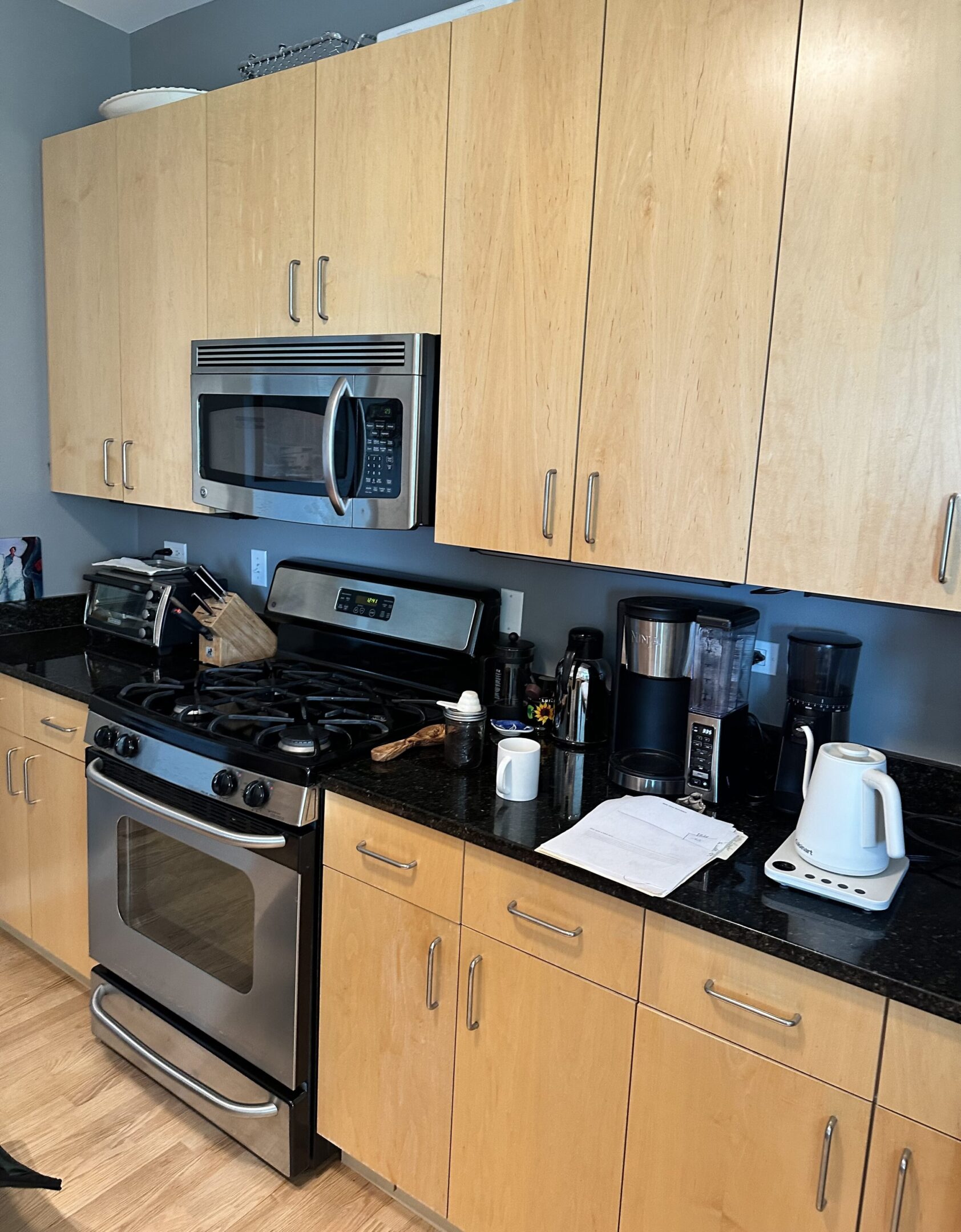 A kitchen with black counter tops and stainless steel appliances.