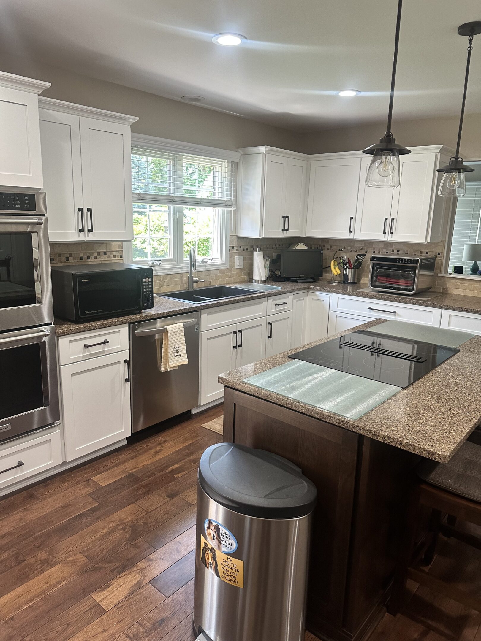 A kitchen with white cabinets and wood floors.