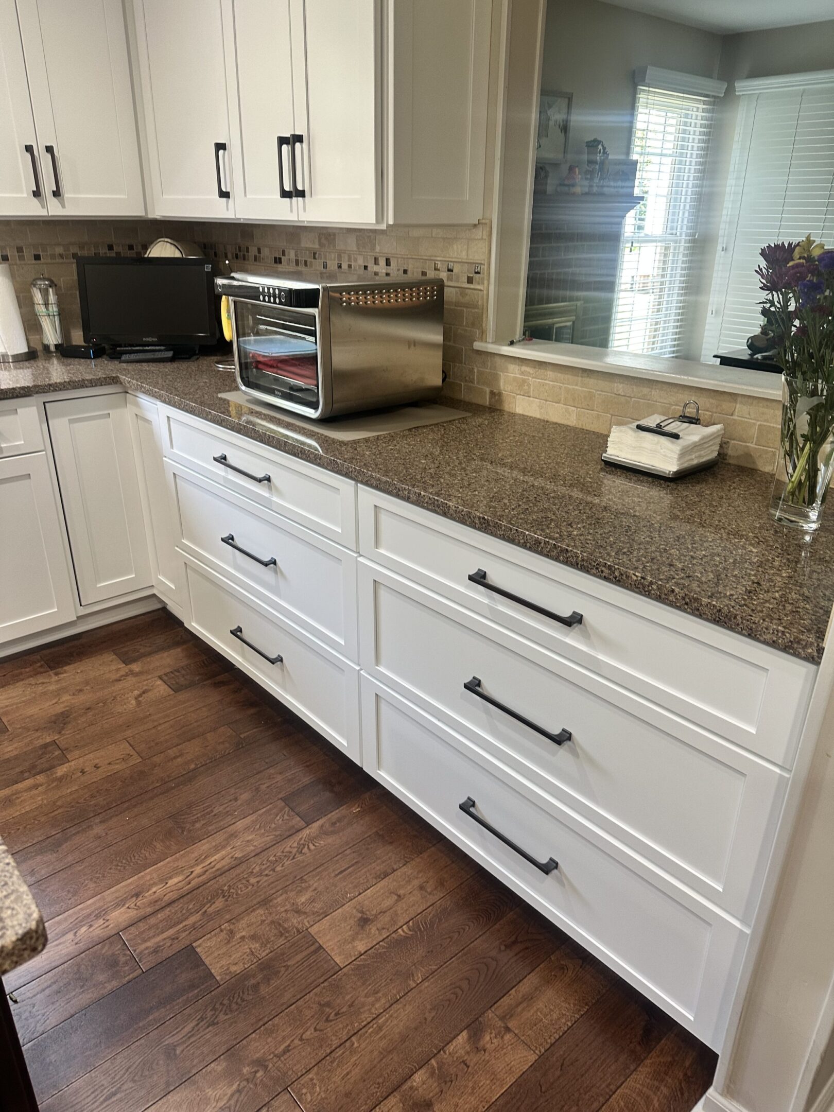 A kitchen with white cabinets and brown countertops.