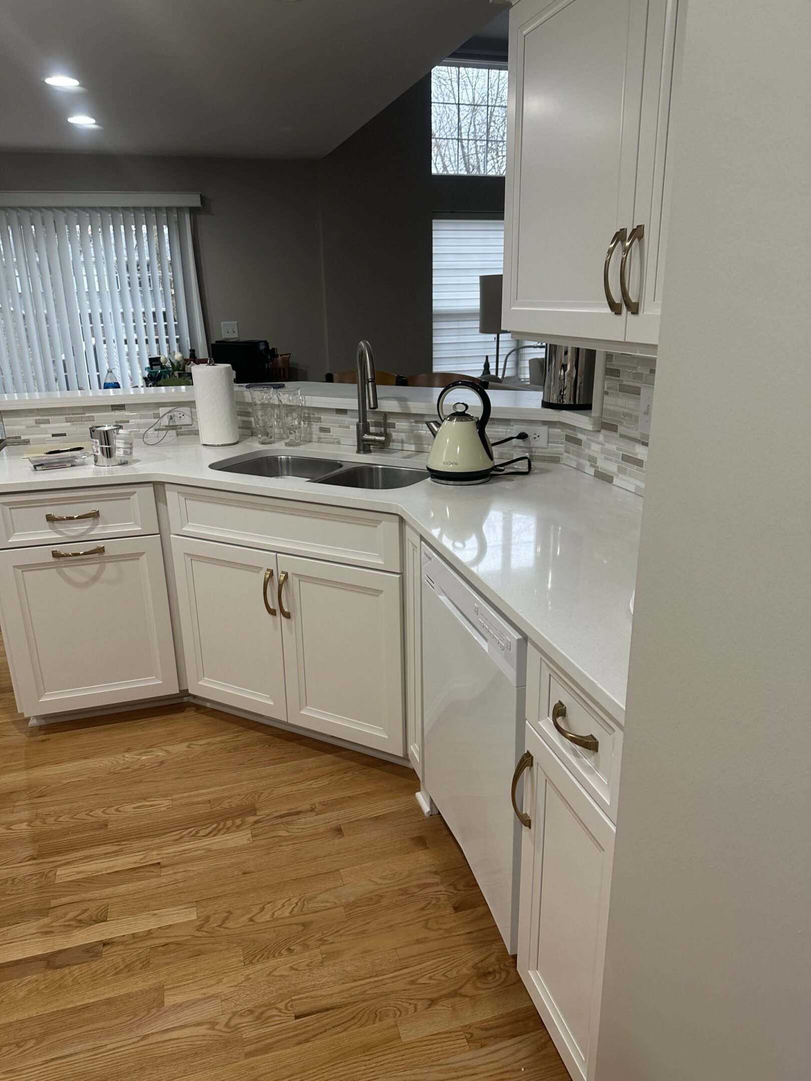 A kitchen with white cabinets and wood floors.