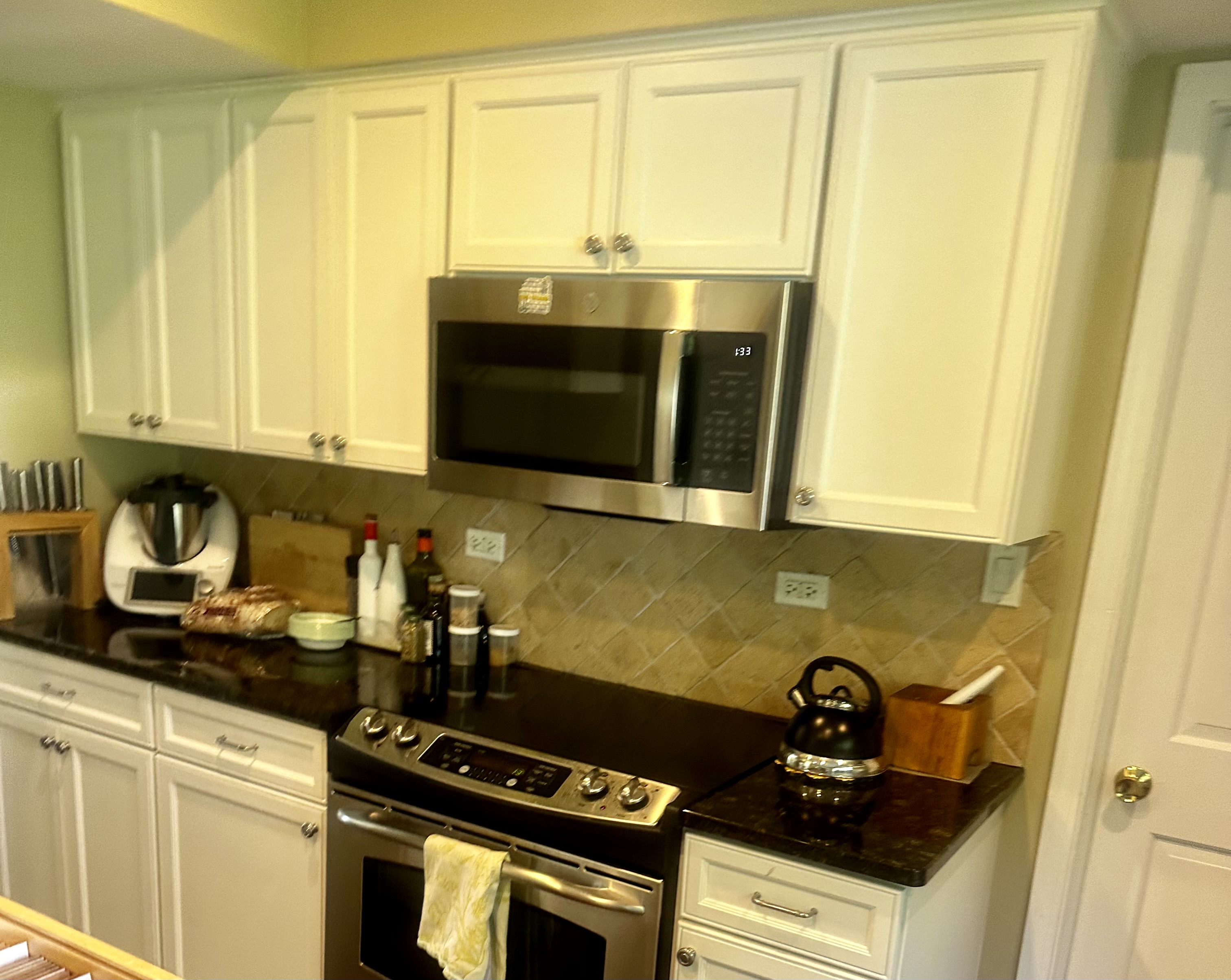 A kitchen with white cabinets and black counter tops.