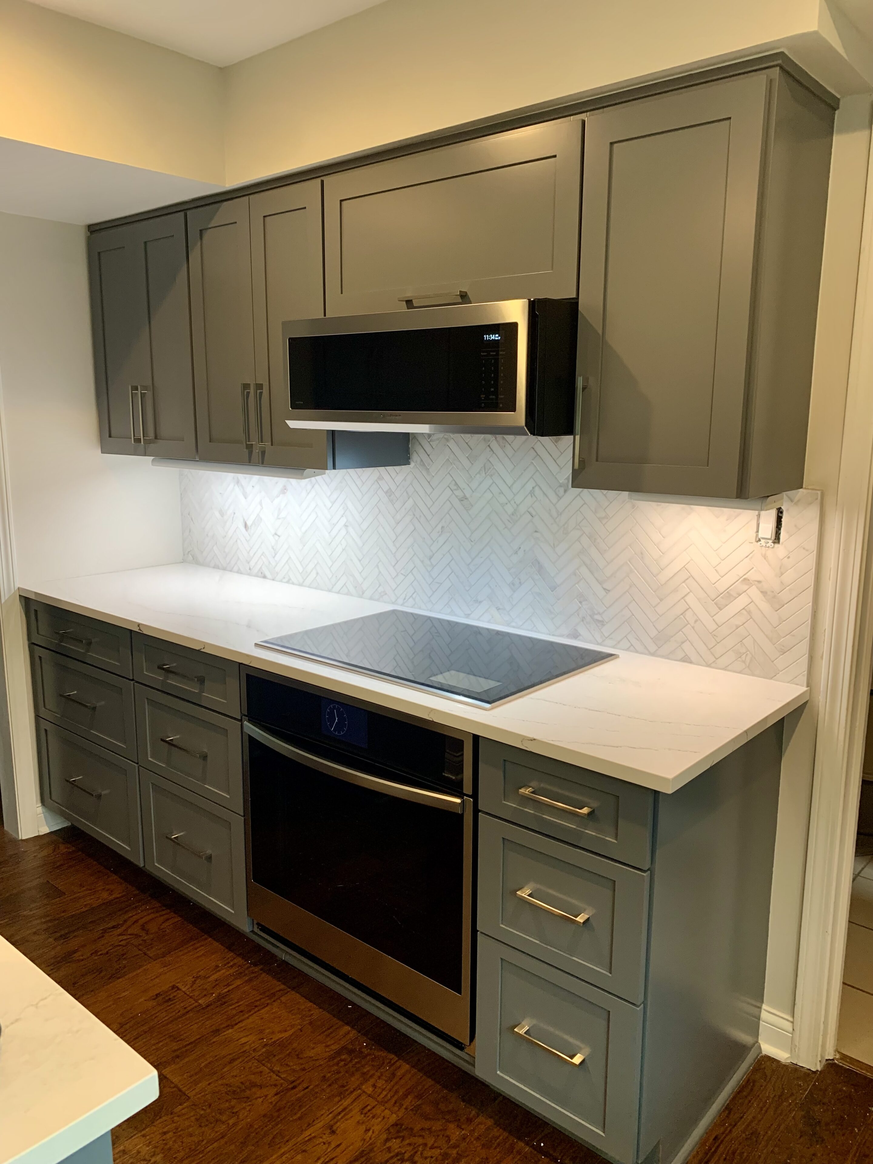 A kitchen with grey cabinets and black appliances.