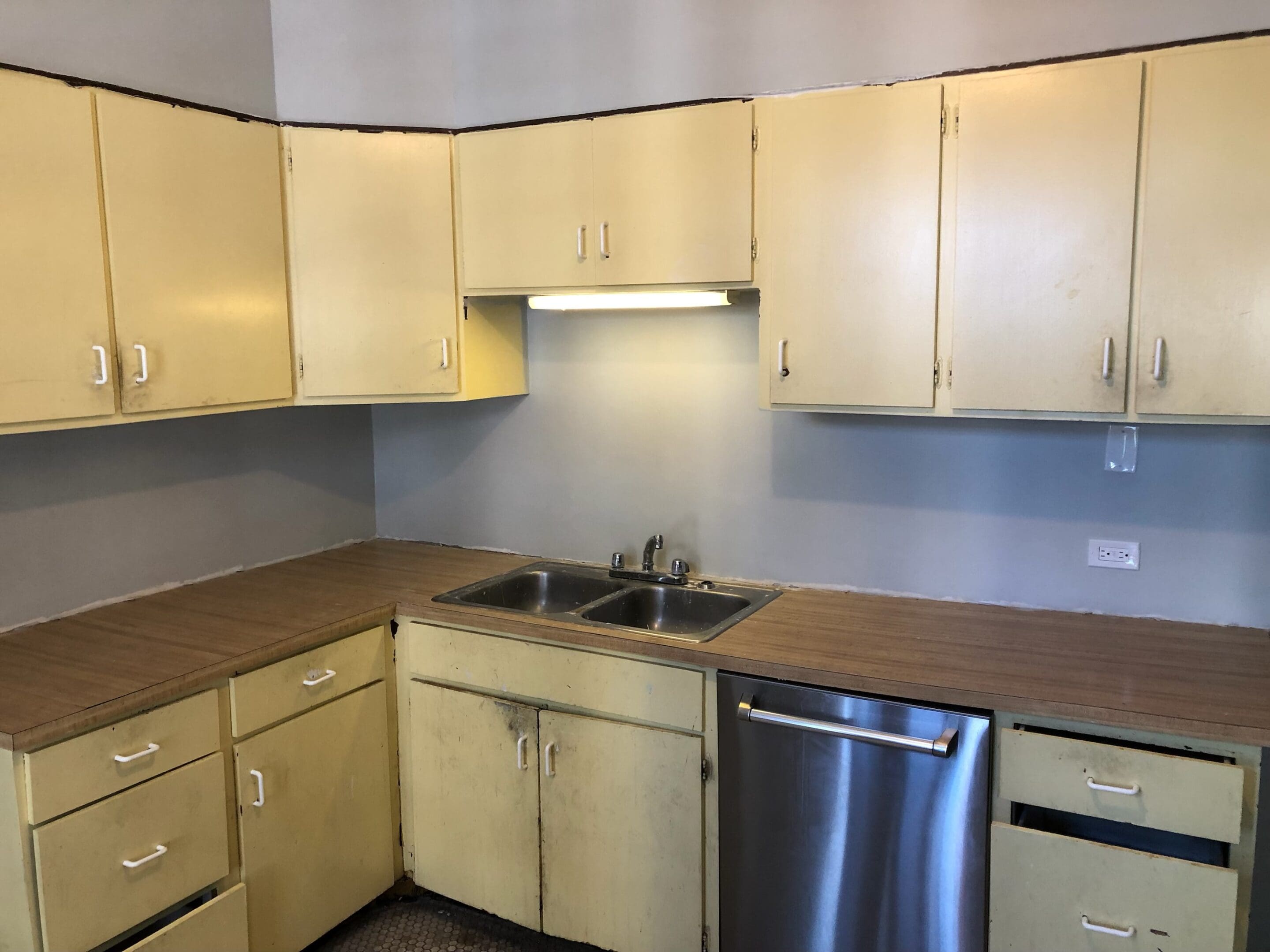 A kitchen with yellow cabinets and stainless steel appliances.