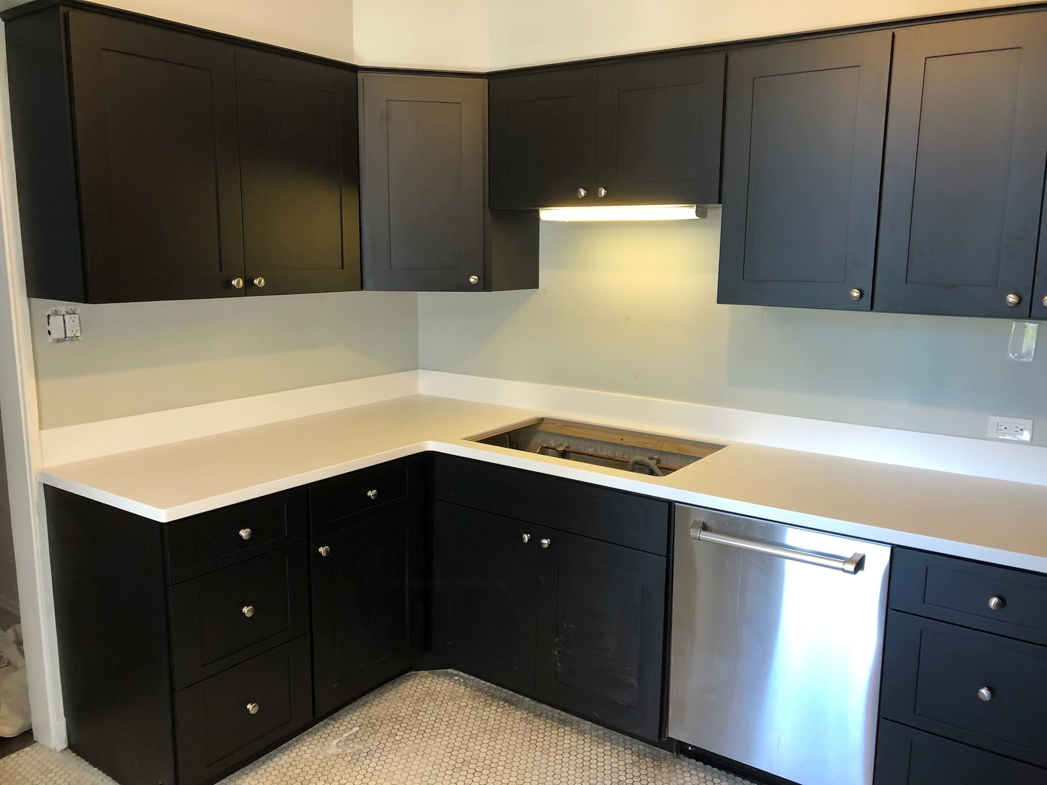 A kitchen with black cabinets and white counters.