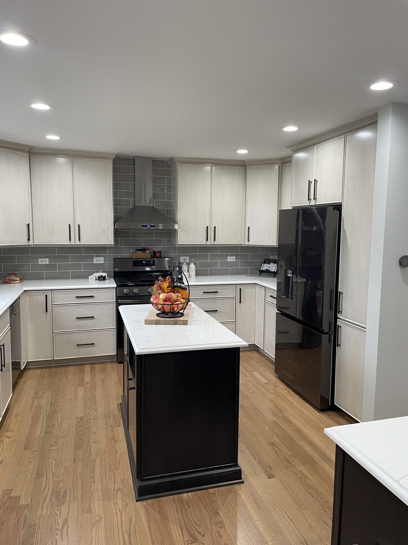 A kitchen with white cabinets and black island.