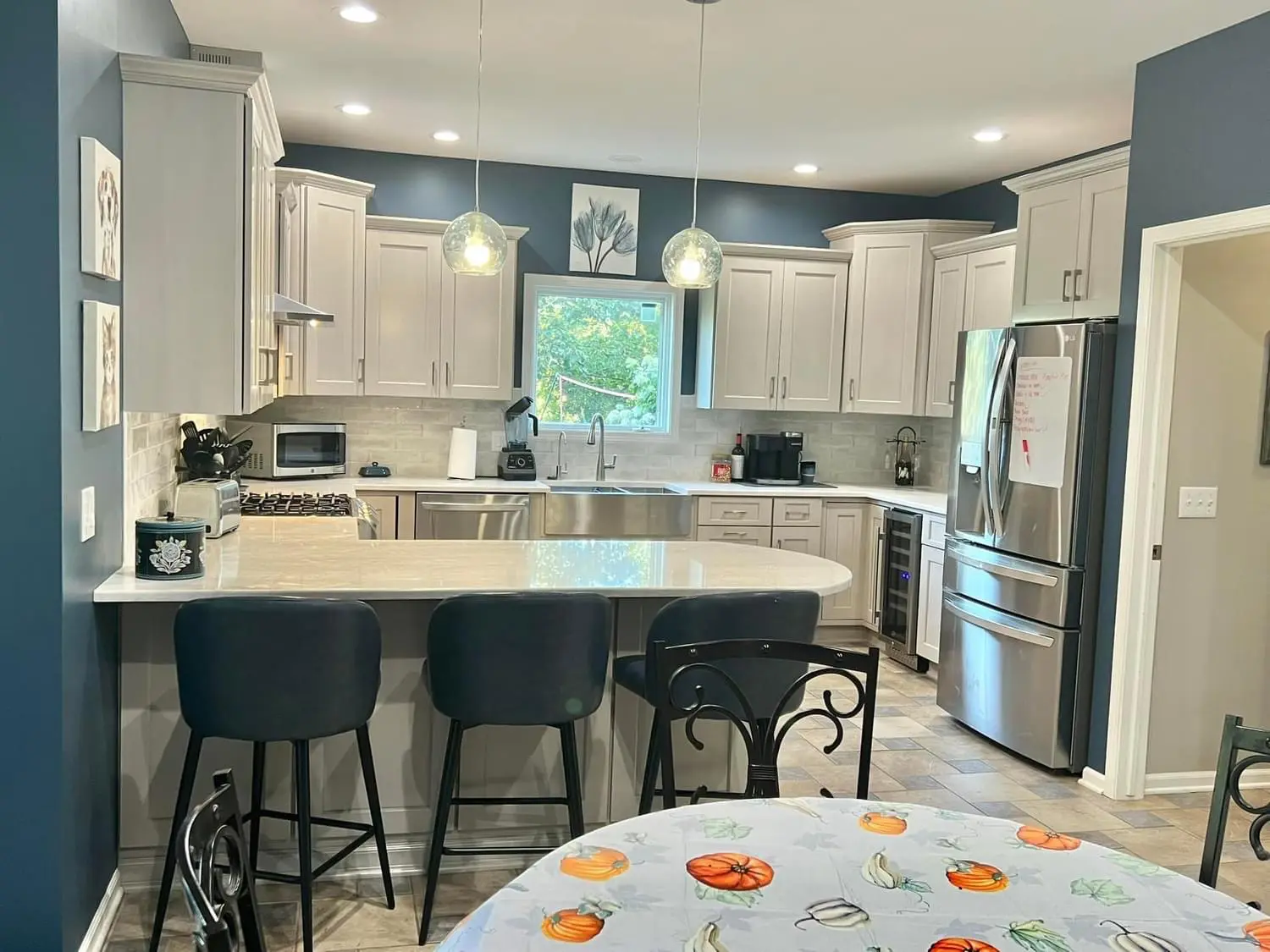 A kitchen with white cabinets and black chairs.