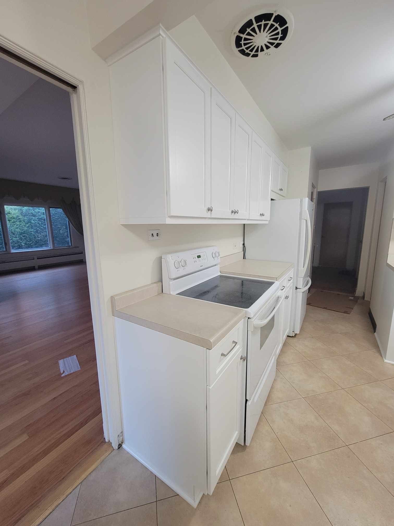 A kitchen with white cabinets and wood floors.